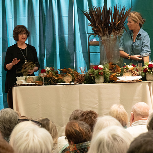 Florists leading a presentation on tablescaping for holiday dinners with large display in front of audience